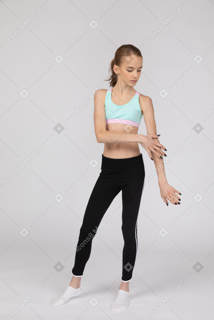 Front view of a teen girl in sportswear outstretching hand and touching arm