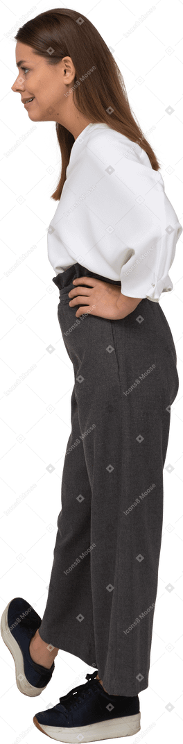 Vista laterale di una giovane donna arrogante in abiti da ufficio che mette le mani sui fianchi