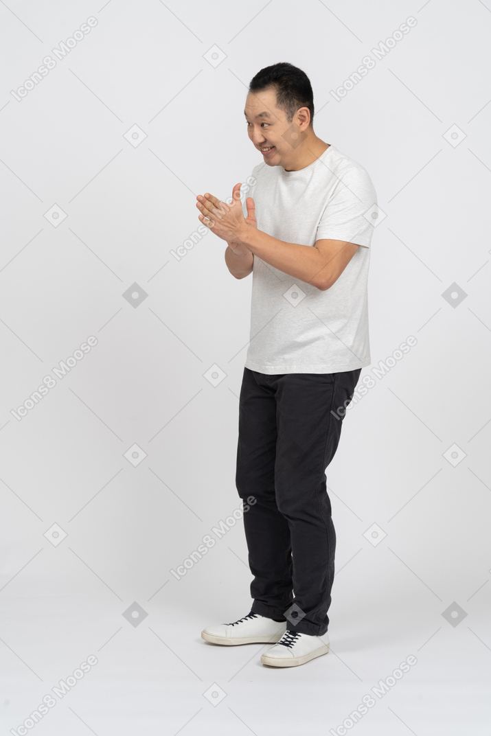 Side view of a cheerful man in casual clothes rubbing hands