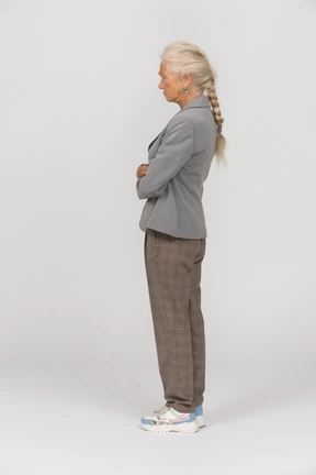 Side view of an old woman in suit standing with crossed arms