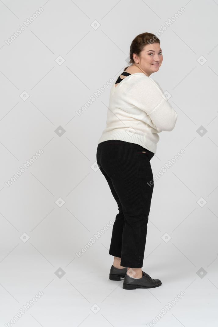 看照相机的一个愉快的肥满妇女的背面图