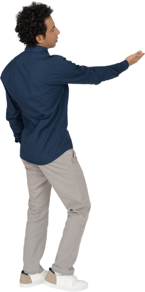 Rear view of a man in casual clothes pointing with hand