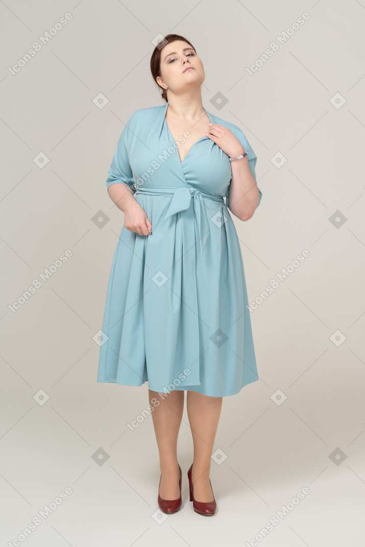 Vista frontal de uma mulher de vestido azul coçando o pescoço