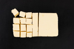 Cut block of butter on black background