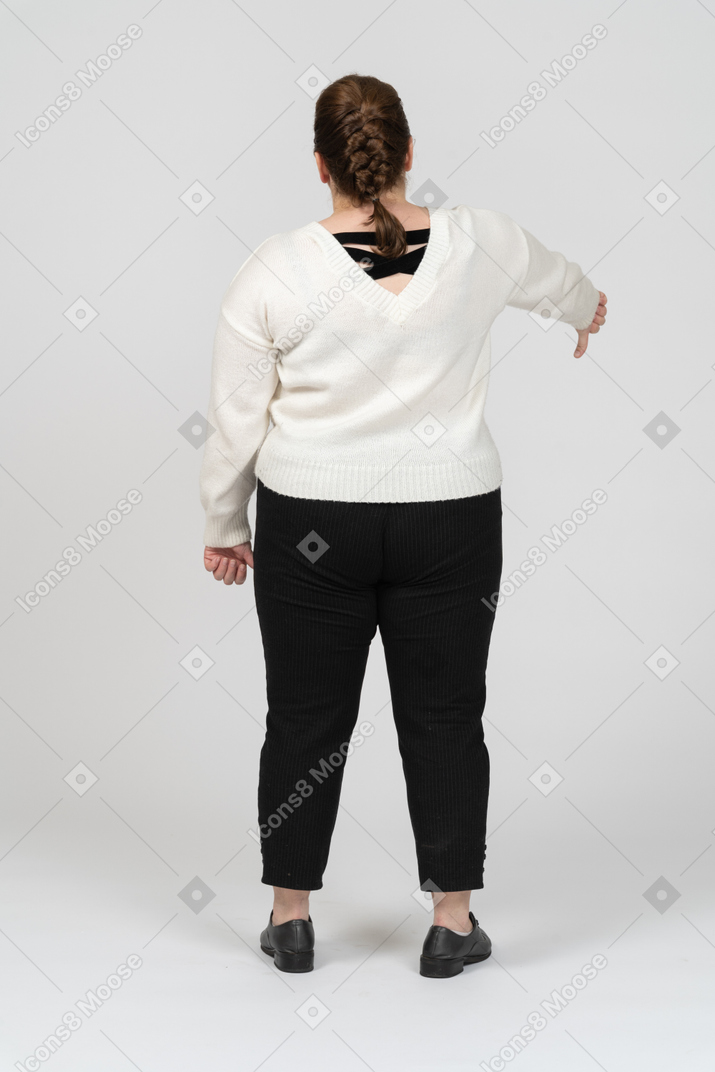 Plus size woman in white sweater showing thumb down