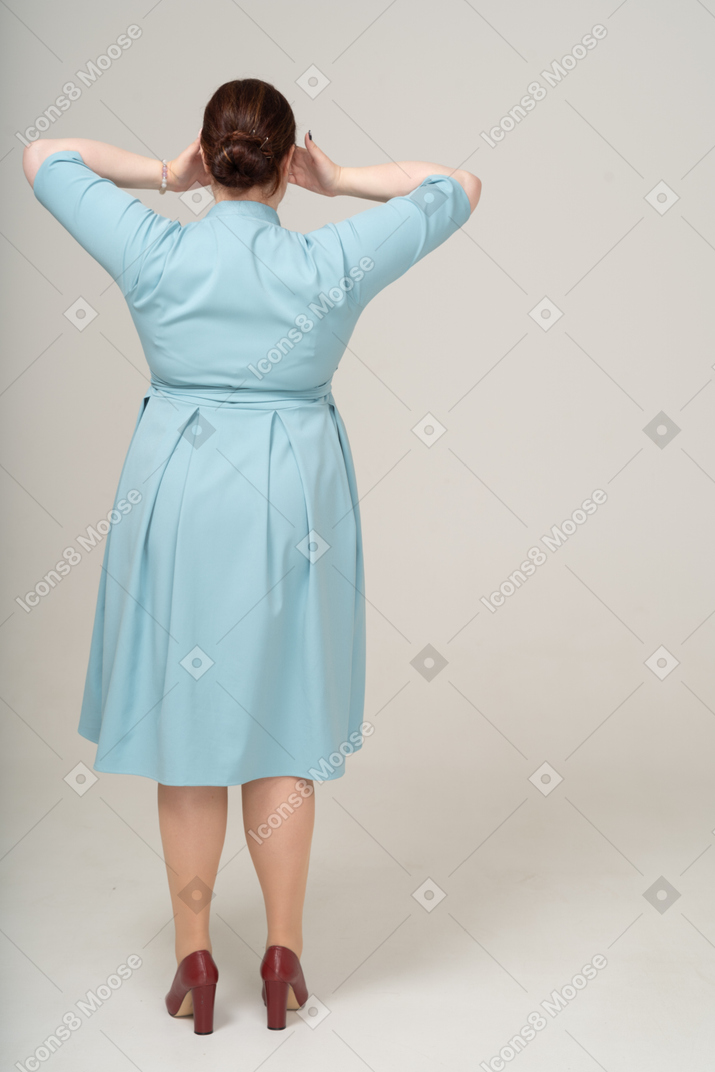 Rear view of a woman in blue dress covering eyes with hands