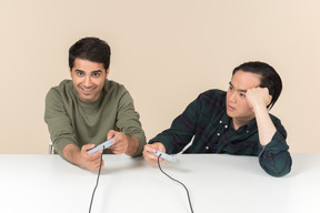 Interracial friends playing video game and one of them looks annoyed