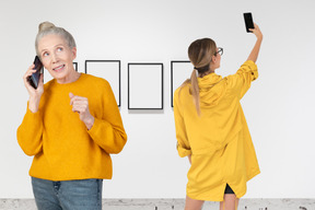 A senior woman talking on the phone while young woman taking a selfie