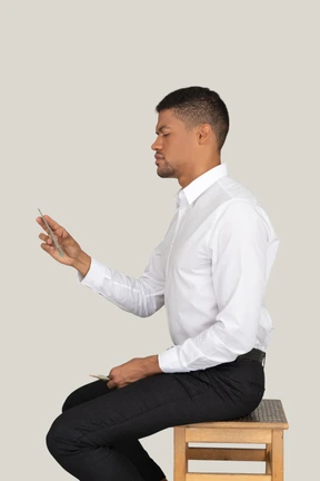 A man sitting on a wooden chair and holding something