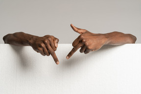 Human hands showing middle fingers behind styrofoam board