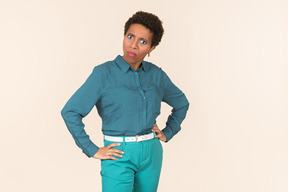 Black woman with a short haircut, wearing all blue, standing against a plain pastel background, looking emotional