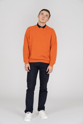 Junger mann im orangefarbenen sweatshirt stehend