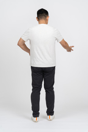 Back view of a man in casual clothes pointing at something with a hand