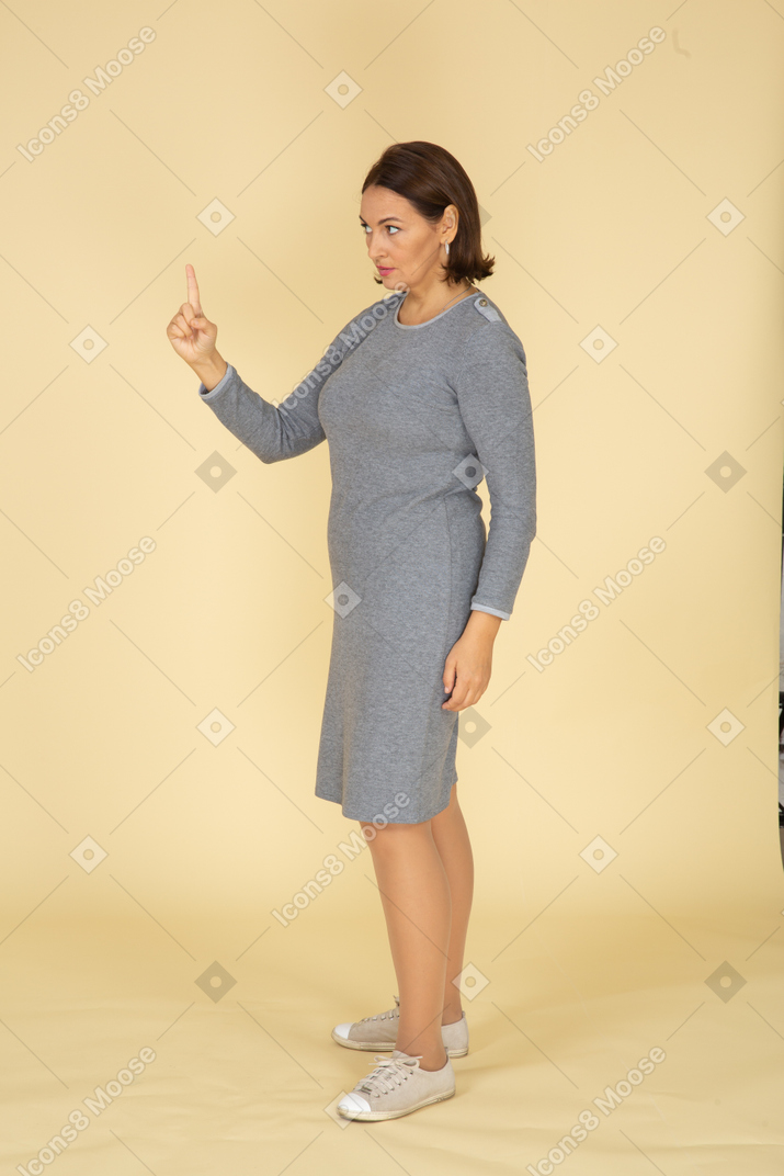 Side view of a woman in grey dress pointing with a finger