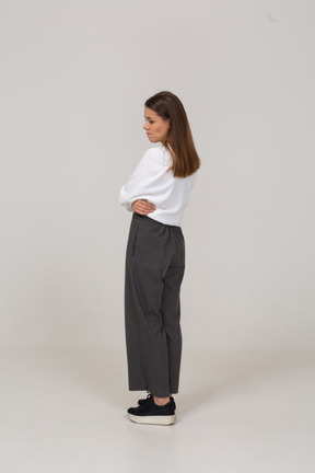 Three-quarter back view of an upset young lady in office clothing putting hands on belly