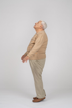 Vue latérale d'un vieil homme en vêtements décontractés debout sur les orteils et levant les yeux