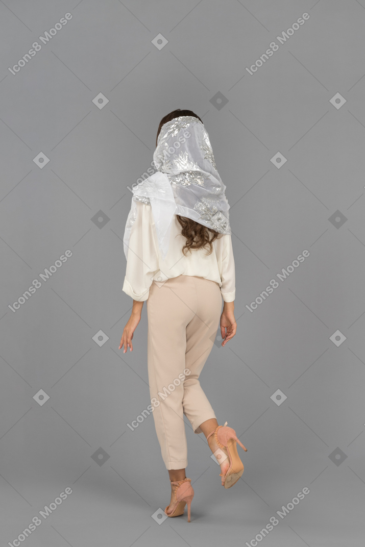Femme couverte méconnaissable, debout devant la caméra