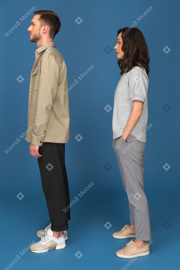 年轻的男人和女人侧身站在相机