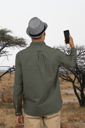 A man standing in a field holding a cell phone
