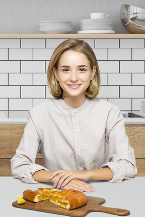 A woman sitting at a table with a lemon pie