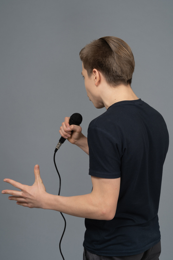 Young man gesturing while speaking into microphone