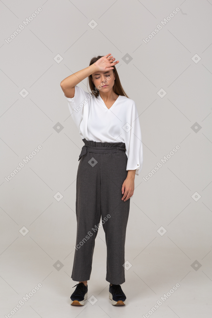 Front view of a young lady in office clothing touching forehead