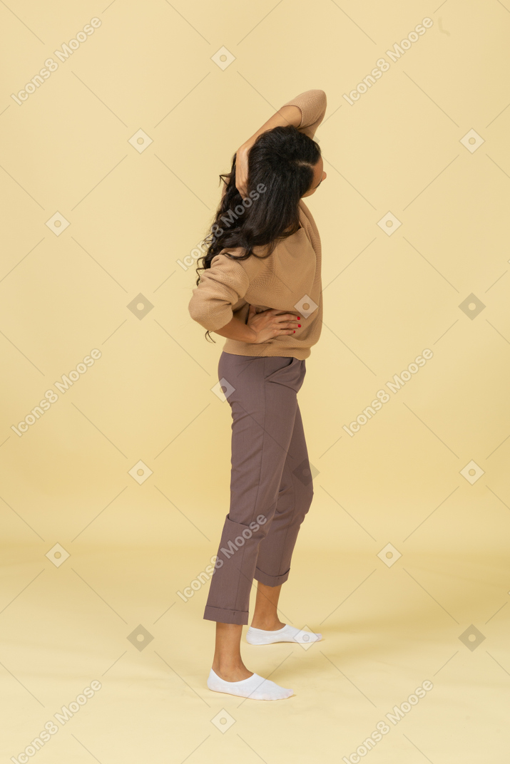Vista lateral de una mujer joven de piel oscura tocando el cabello