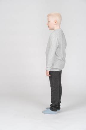 Vista lateral de un niño chico parado y mirando a un lado