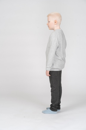 Side view of a kid boy standing still and looking aside