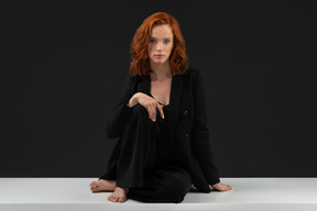 A frontal view of the young beautiful woman sitting on the table and looking to the camera