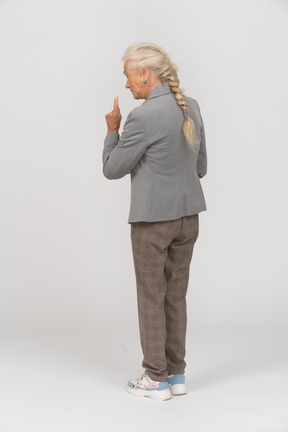 Rear view of an old lady in suit making a warning sign