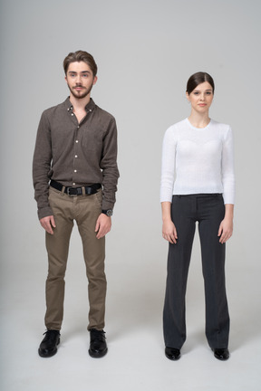 Front view of a young couple in office clothing standing still