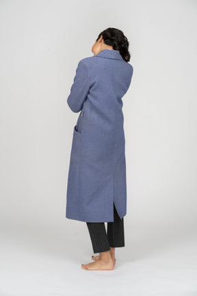 Rear view of a woman in coat standing