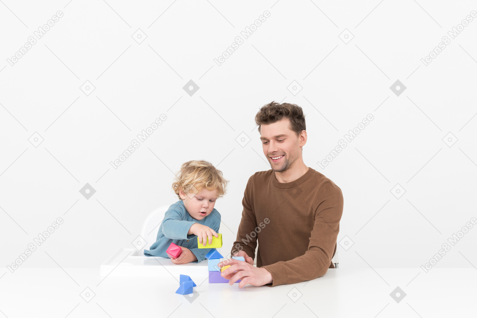 父亲坐在桌前和他的儿子一起玩