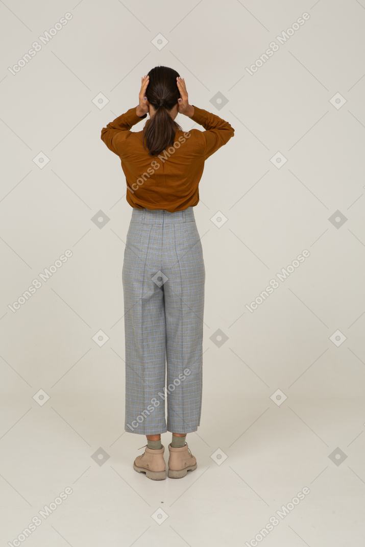 Vue arrière d'une jeune femme asiatique en culotte et chemisier touchant la tête