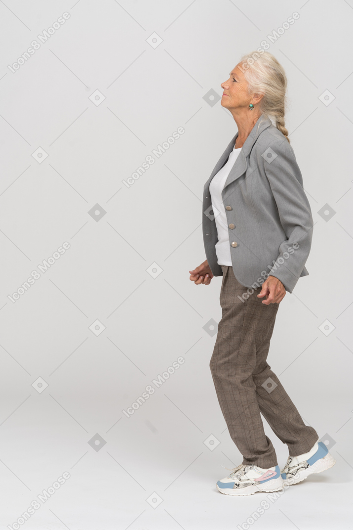 Vista laterale di una vecchia signora in abito che cammina