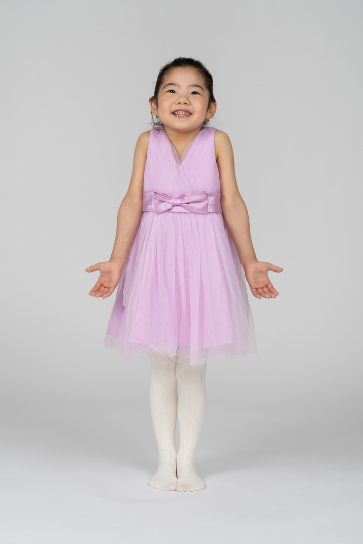 Portrait of a little girl shrugging in a pretty dress