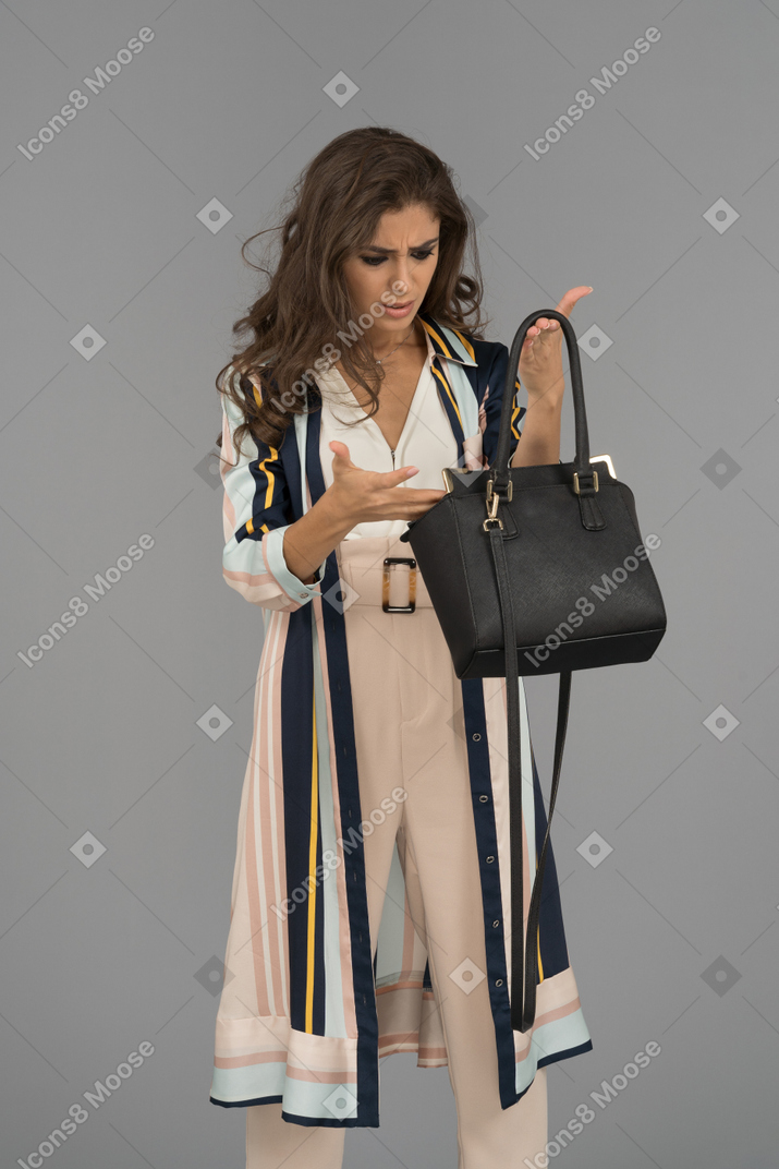 Annoyed young woman looking inside her handbag