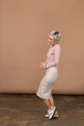 Vista lateral de una mujer feliz en ropa casual posando sobre una pierna