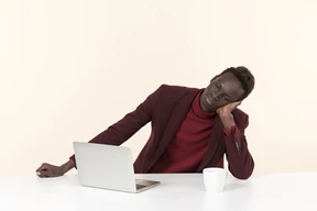 Elegante hombre negro sentado a la mesa en la oficina