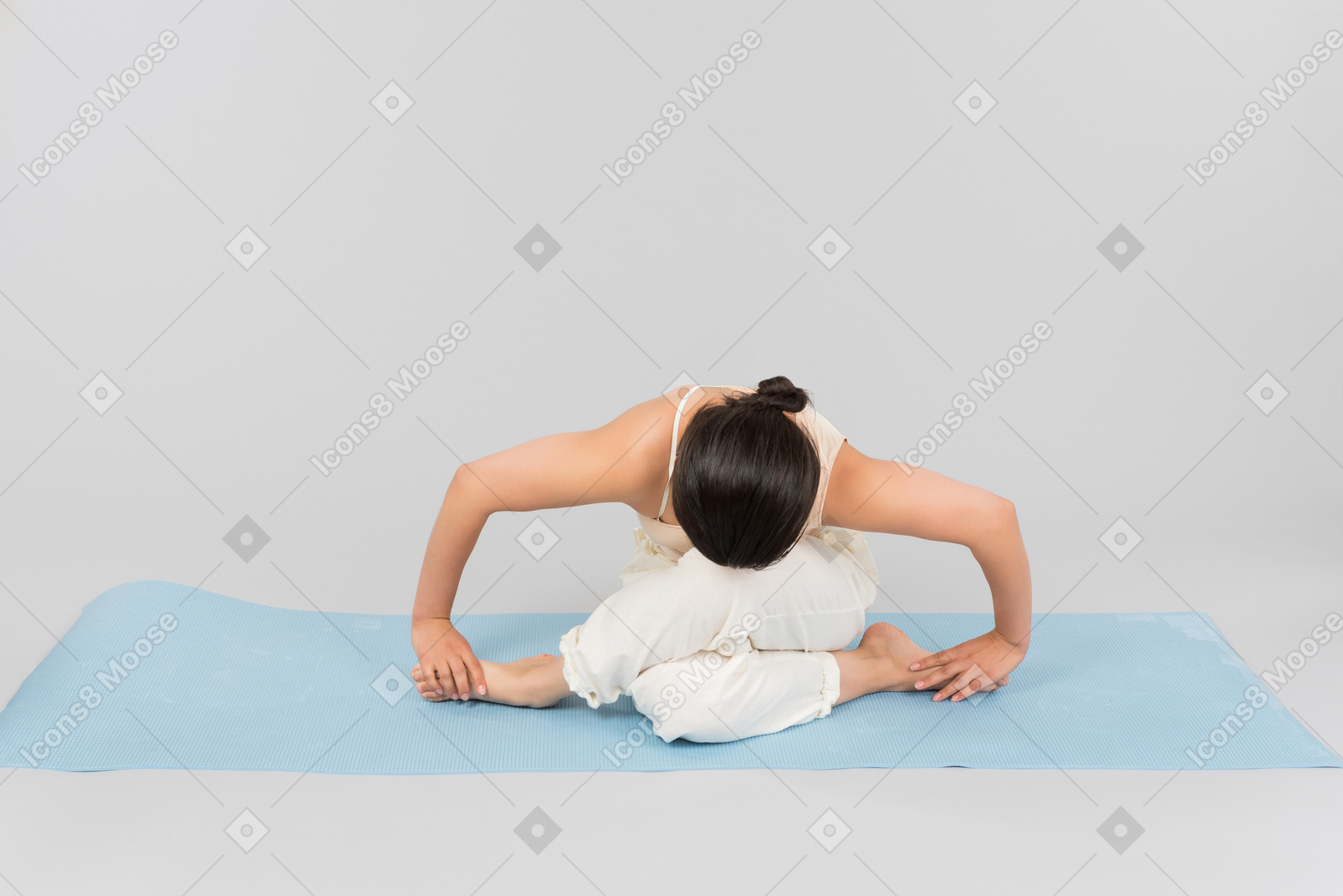 Giovane donna indiana che si siede nella posa di yoga sulla stuoia di yoga