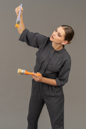 Woman in gray coveralls choosing a paint brush