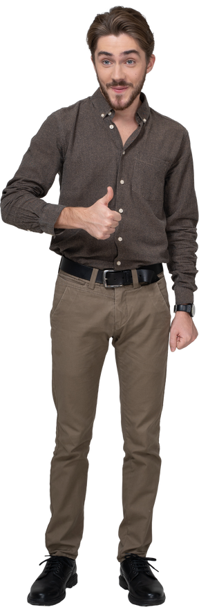 Вид спереди веселого молодого человека в офисной одежде, показывающего большой палец вверх