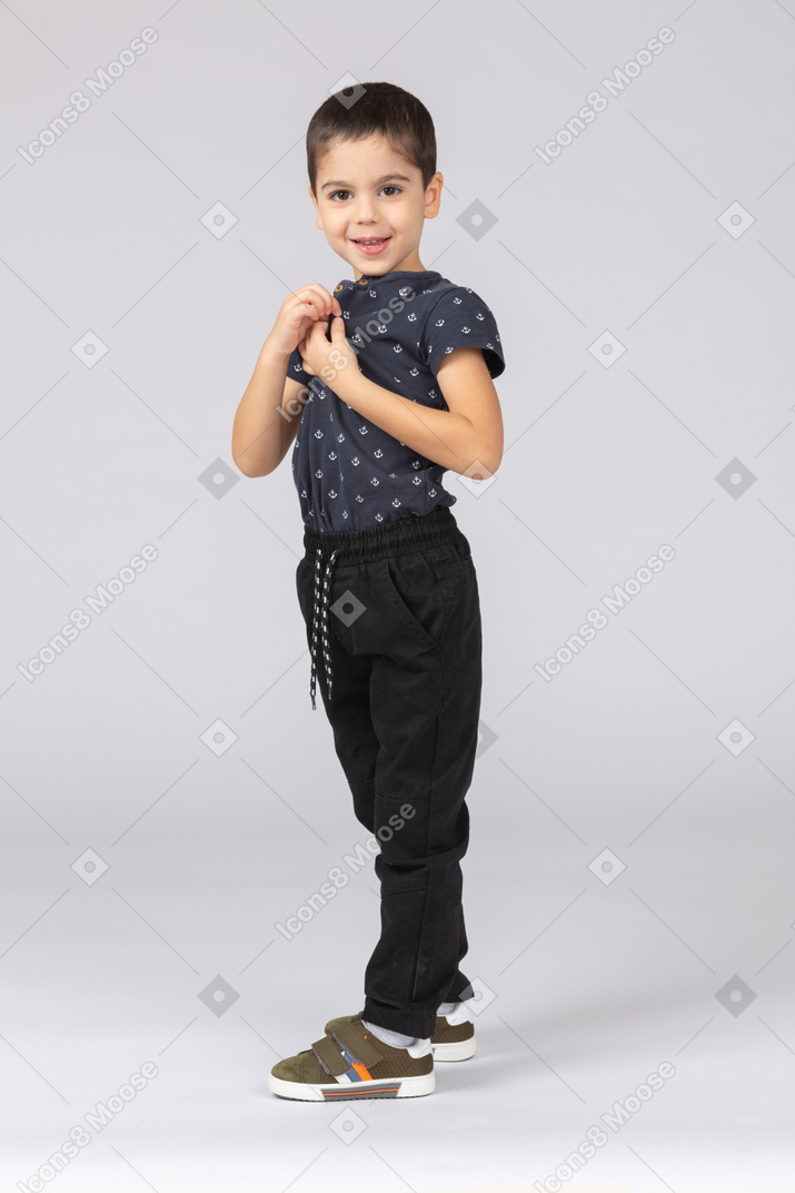 Vista lateral de un niño feliz en ropa casual mirando a la cámara