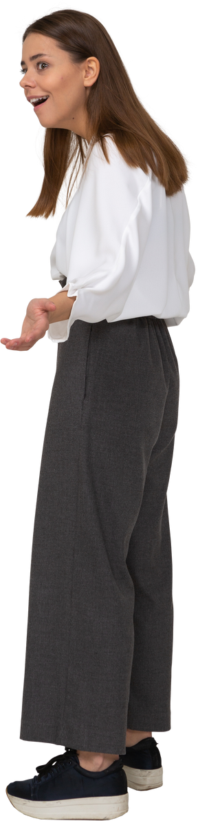 Vista lateral de uma jovem maravilhada com roupas de escritório estendendo as mãos