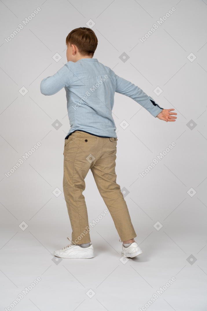 A boy in a blue shirt swinging his arm back