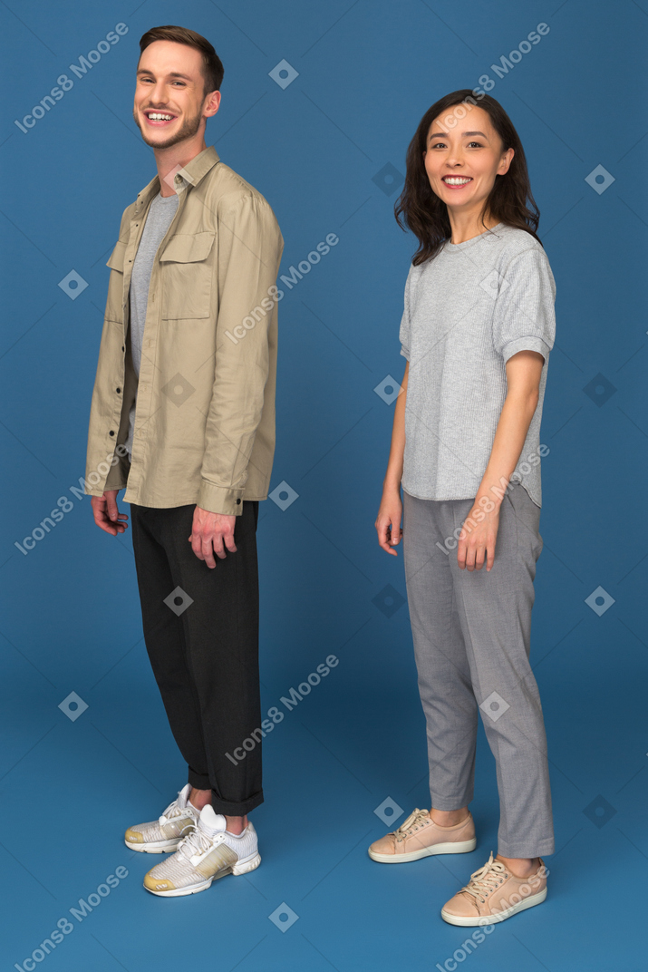 Sonriente hombre y mujer de pie medio volcado a la cámara