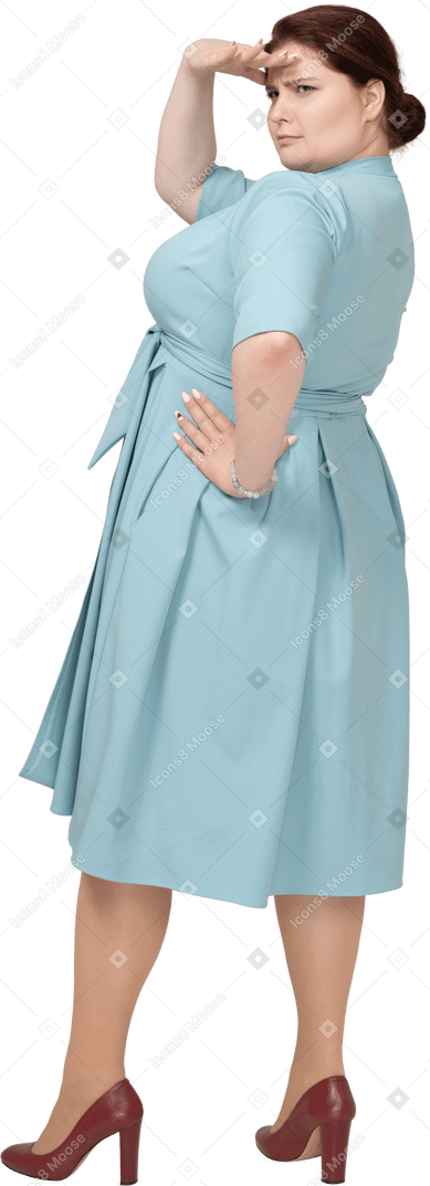 誰かを探している青いドレスを着た女性の背面図