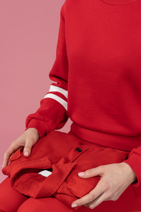 Mujer sosteniendo un polo rojo sobre sus rodillas