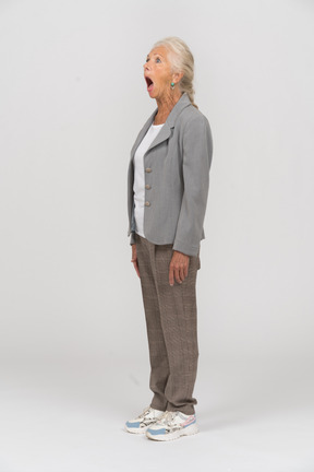一个穿着西装的老妇人张开嘴站着的侧视图
